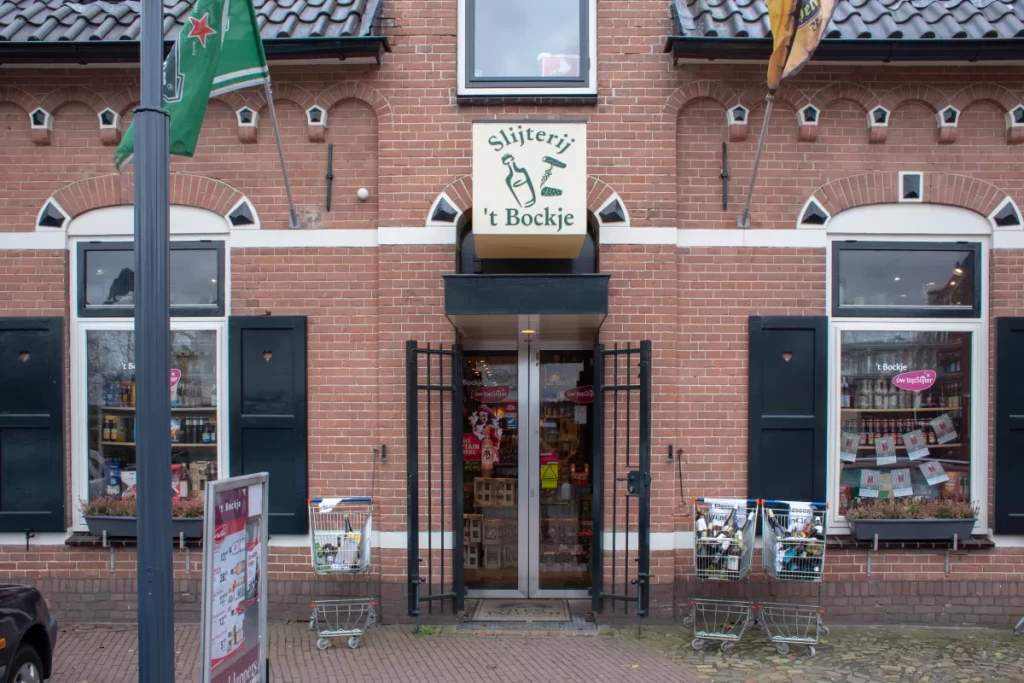 The entrance to the ’t Bockje shop: an open glass door beneath the shop sign, with a display window and green shutters on either side