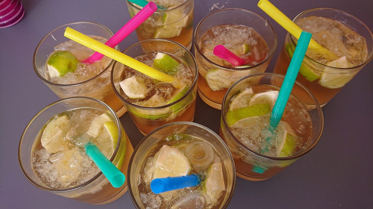 Acht glazen ginger ale met limoen, ijsblokjes en rietjes op een tafel