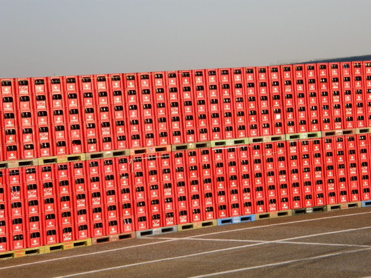 Rijen bierkratten gestapeld op pallets op een bedrijfsterrein