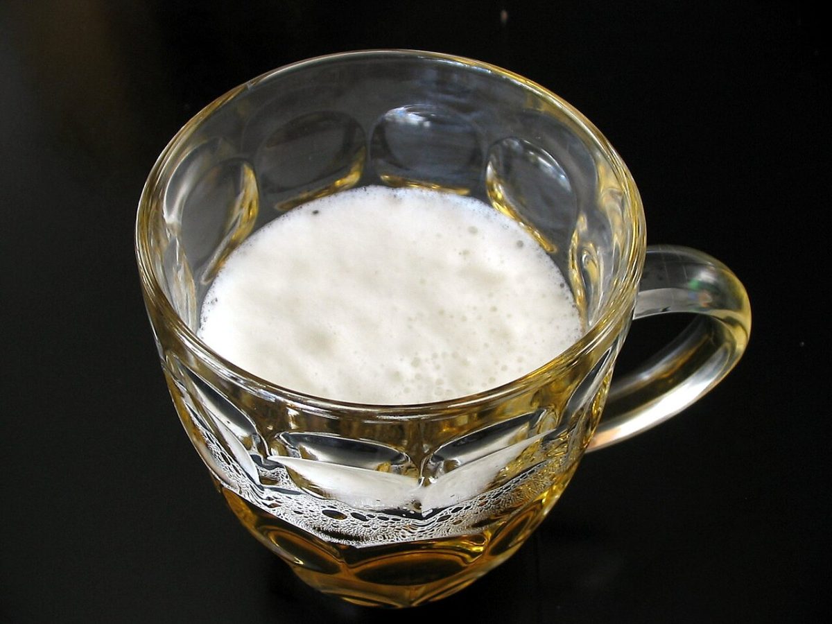 Een bierpul met schuimkraag van bovenaf gezien