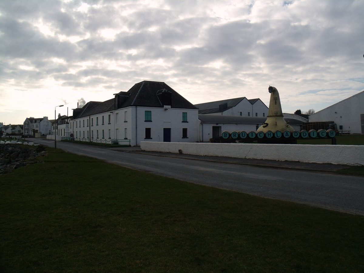 De witgekalkte gebouwen van de Bruichladdich-distilleerderij langs de weg op Islay, met een pagodedak erboven