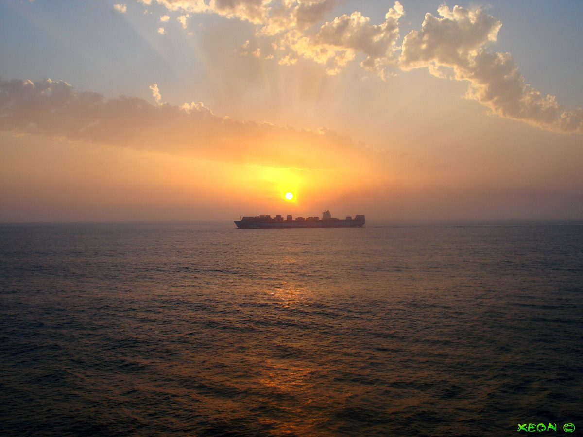 Een containerschip aan de horizon op open zee bij zonsondergang