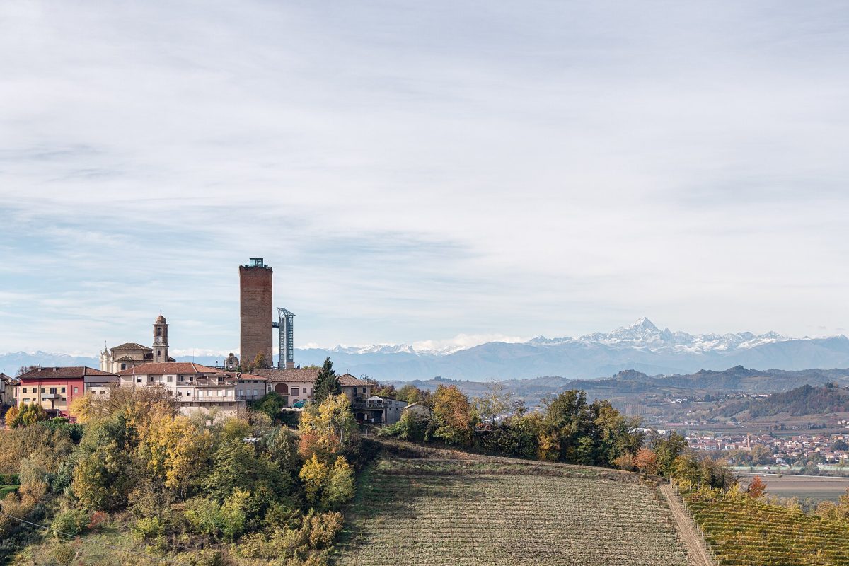 Het dorp Barbaresco met zijn hoge toren, met de besneeuwde Alpen op de achtergrond