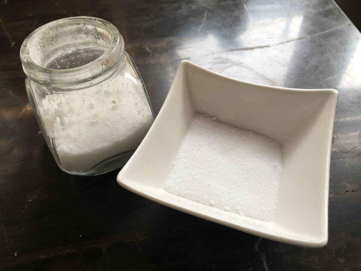 Fijn wit zout in een vierkant schaaltje naast een glazen pot