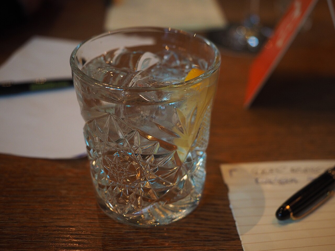 Een glas gin-tonic met ijs op een houten tafel