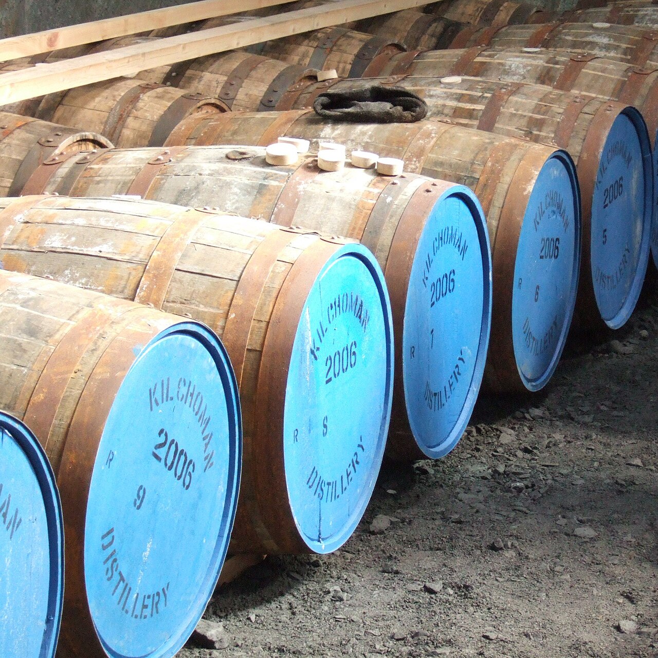 Liggende whiskyvaten met blauw geverfde bodems waarop Kilchoman Distillery 2006 staat