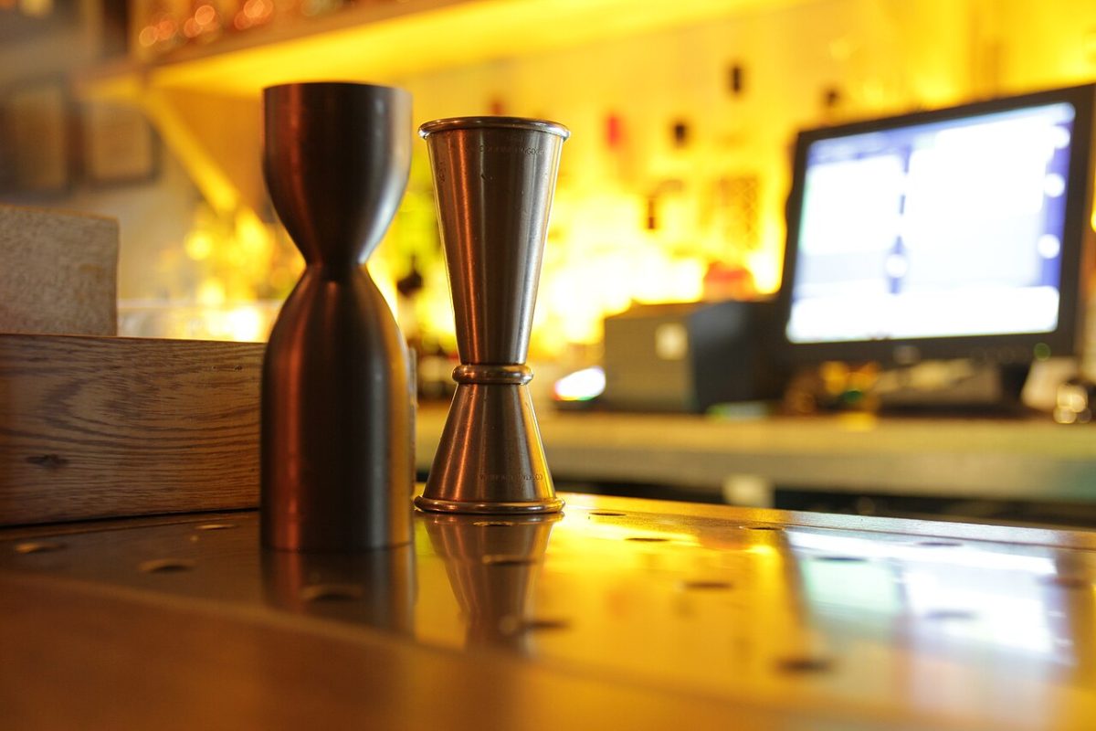 Twee metalen maatbekers op een houten bar