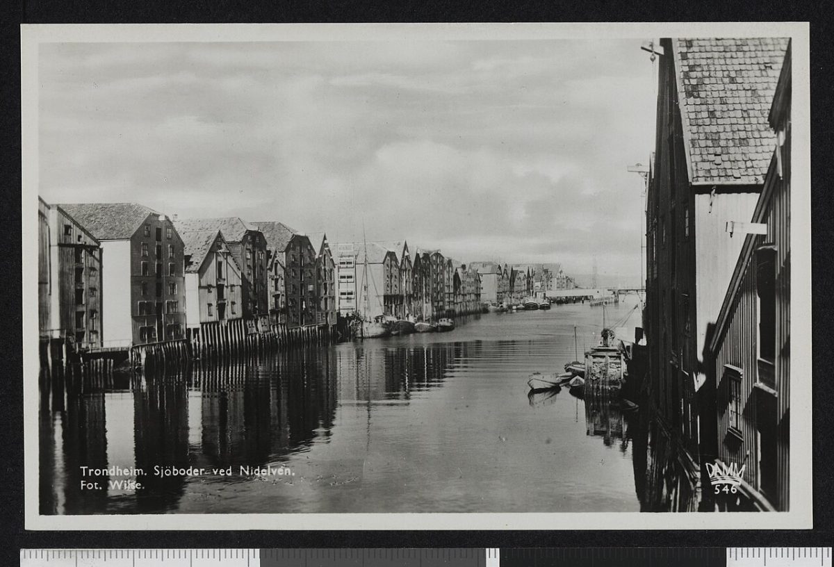 Oude zwart-witopname van houten pakhuizen op palen langs de rivier Nidelva in Trondheim
