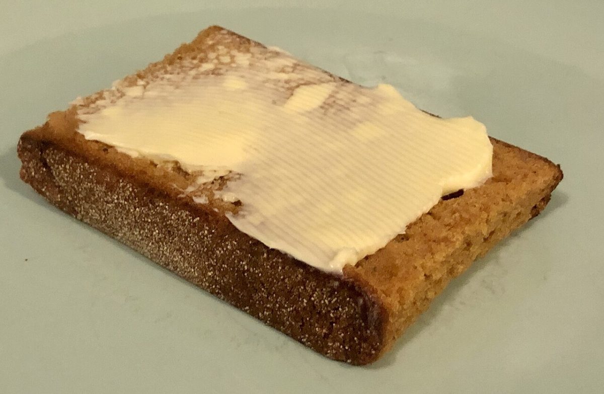 Een plak ontbijtkoek met boter erop