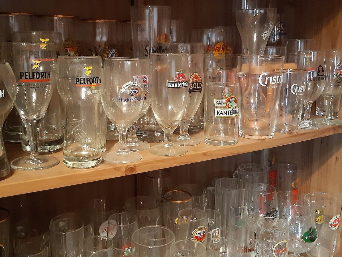 Een plank met tientallen verschillende bierglazen naast elkaar
