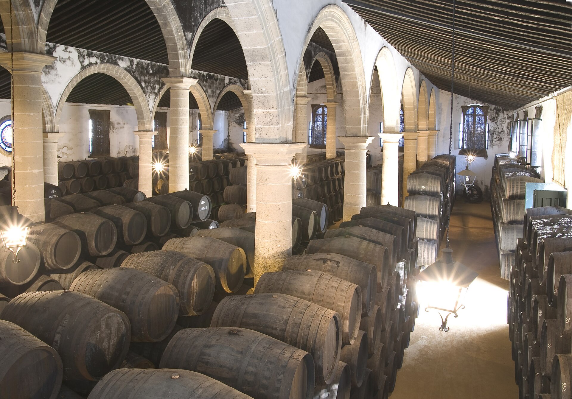 Rijen eikenhouten sherryvaten onder de bogen van bodega La Emperatriz van Lustau in Jerez