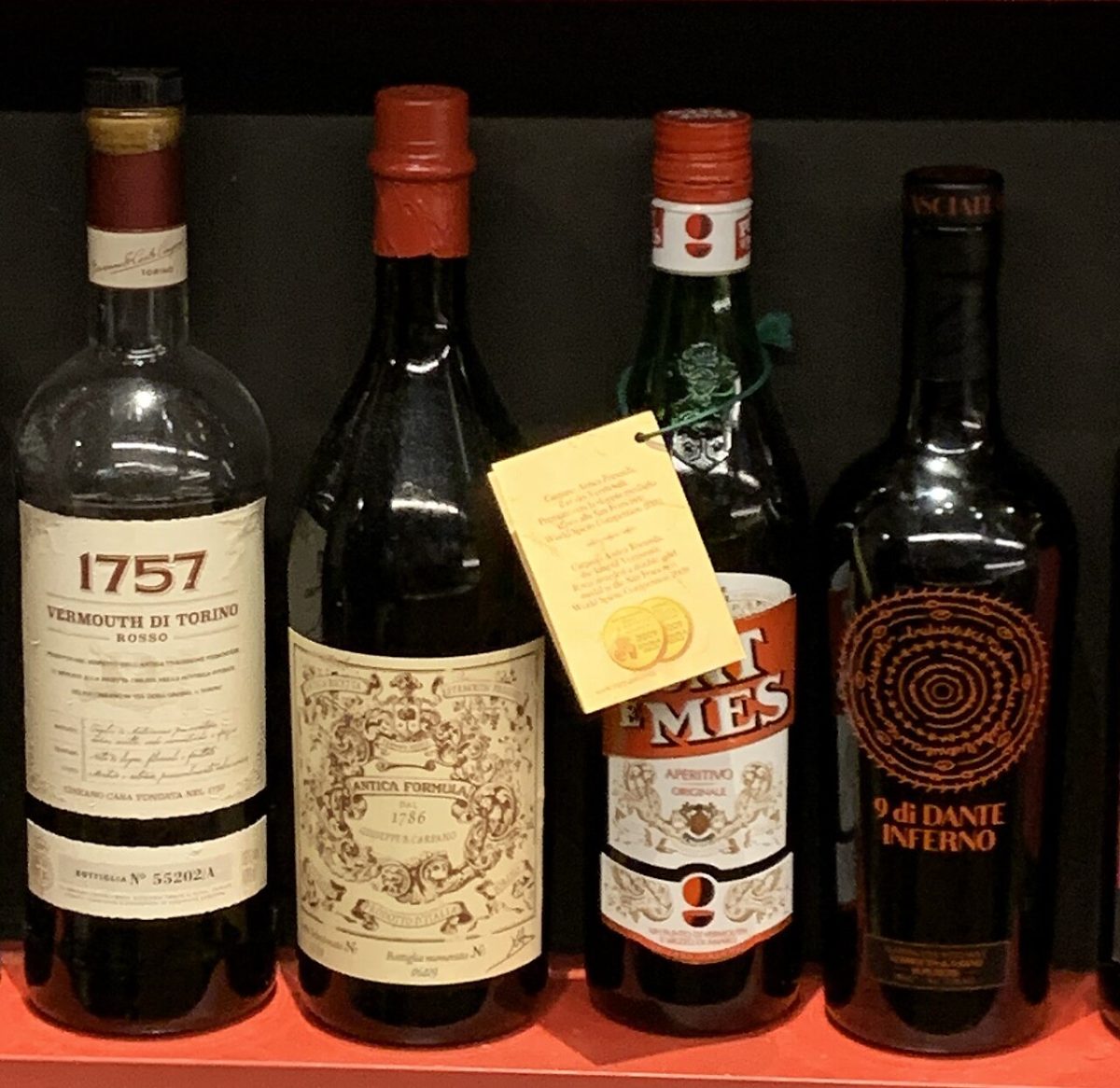 Vier flessen vermouth di Torino naast elkaar op een plank