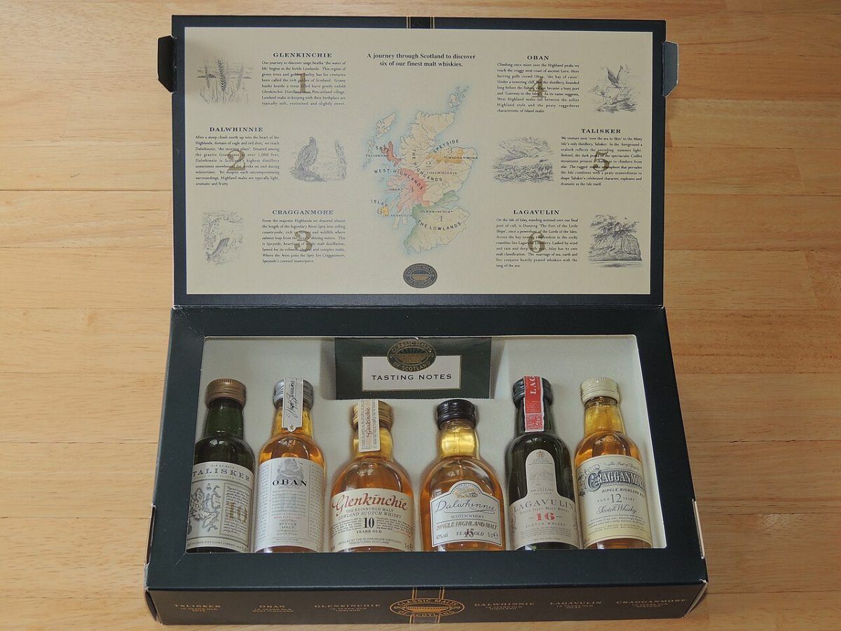 Zes kleine whiskyflessen in een open geschenkkist met een kaart in het deksel