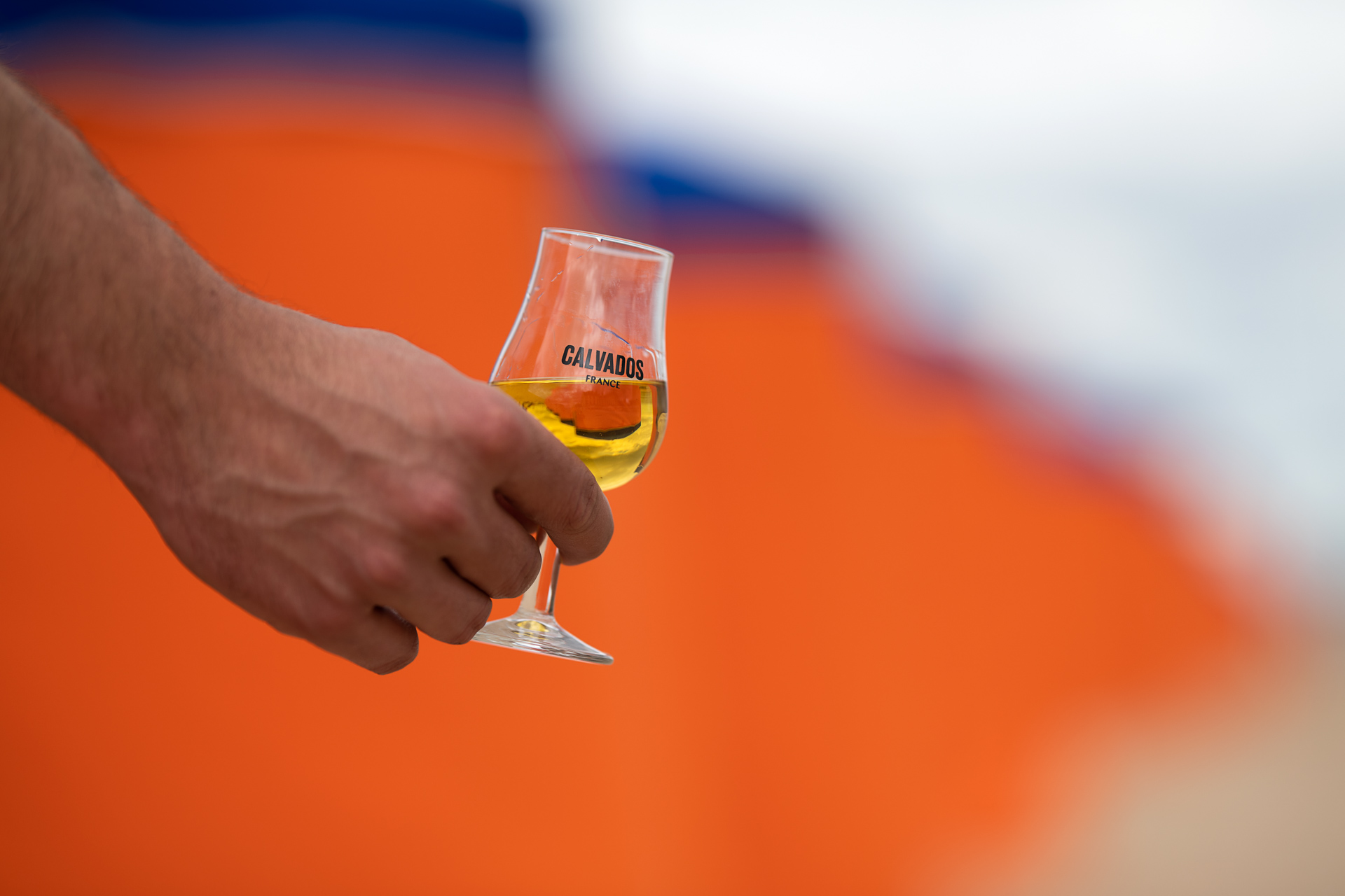 Een hand houdt een tulpvormig proefglas met amberkleurige drank vast