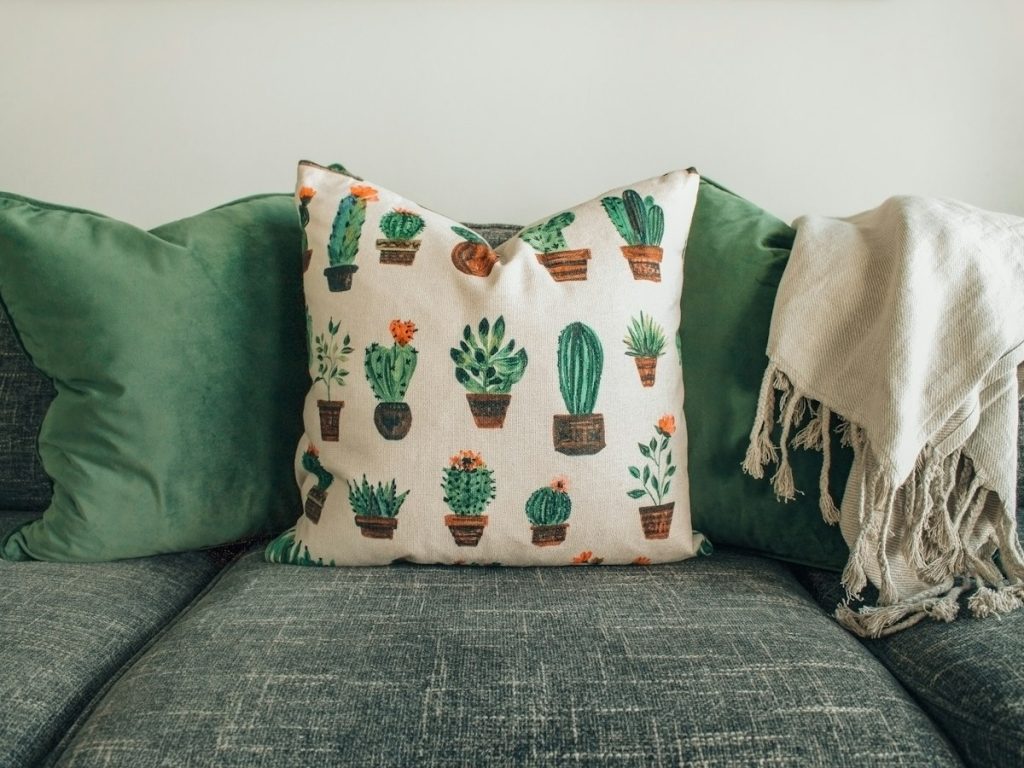 A grey sofa with cushion covers and a white throw