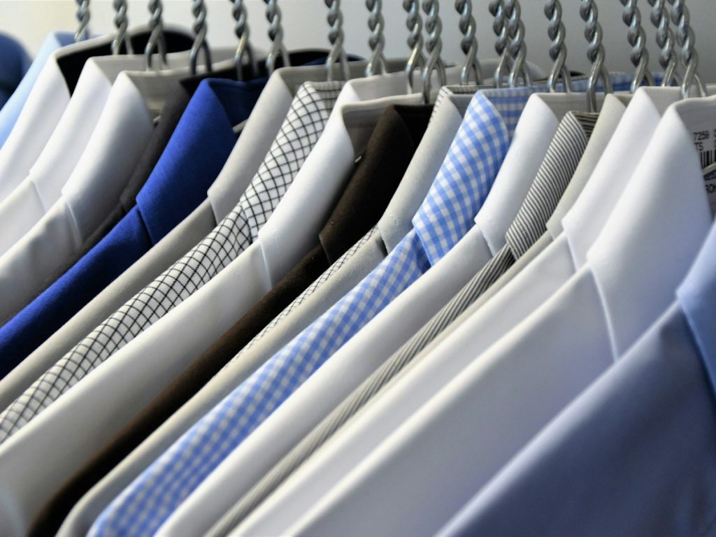 White and blue shirts side by side on hangers on a clothes rail