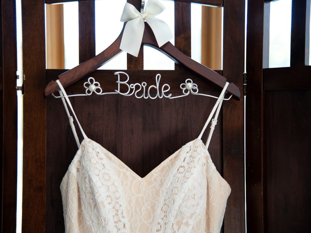 A wedding dress on a wooden hanger with the word Bride on it