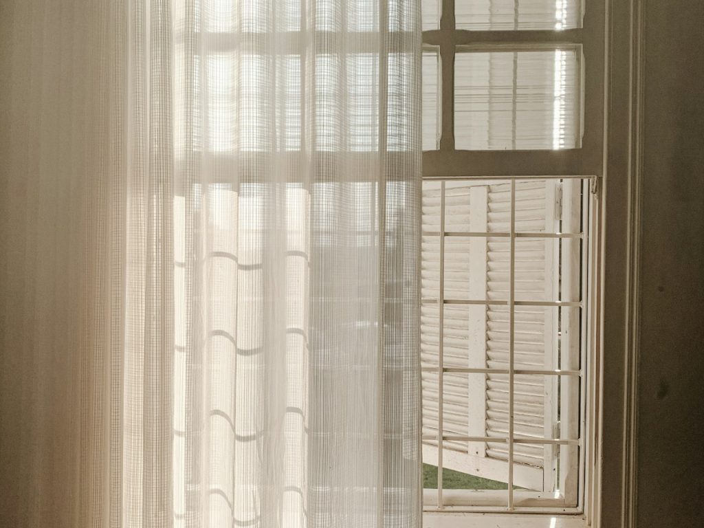 White net curtains at a window, with sunlight shining through