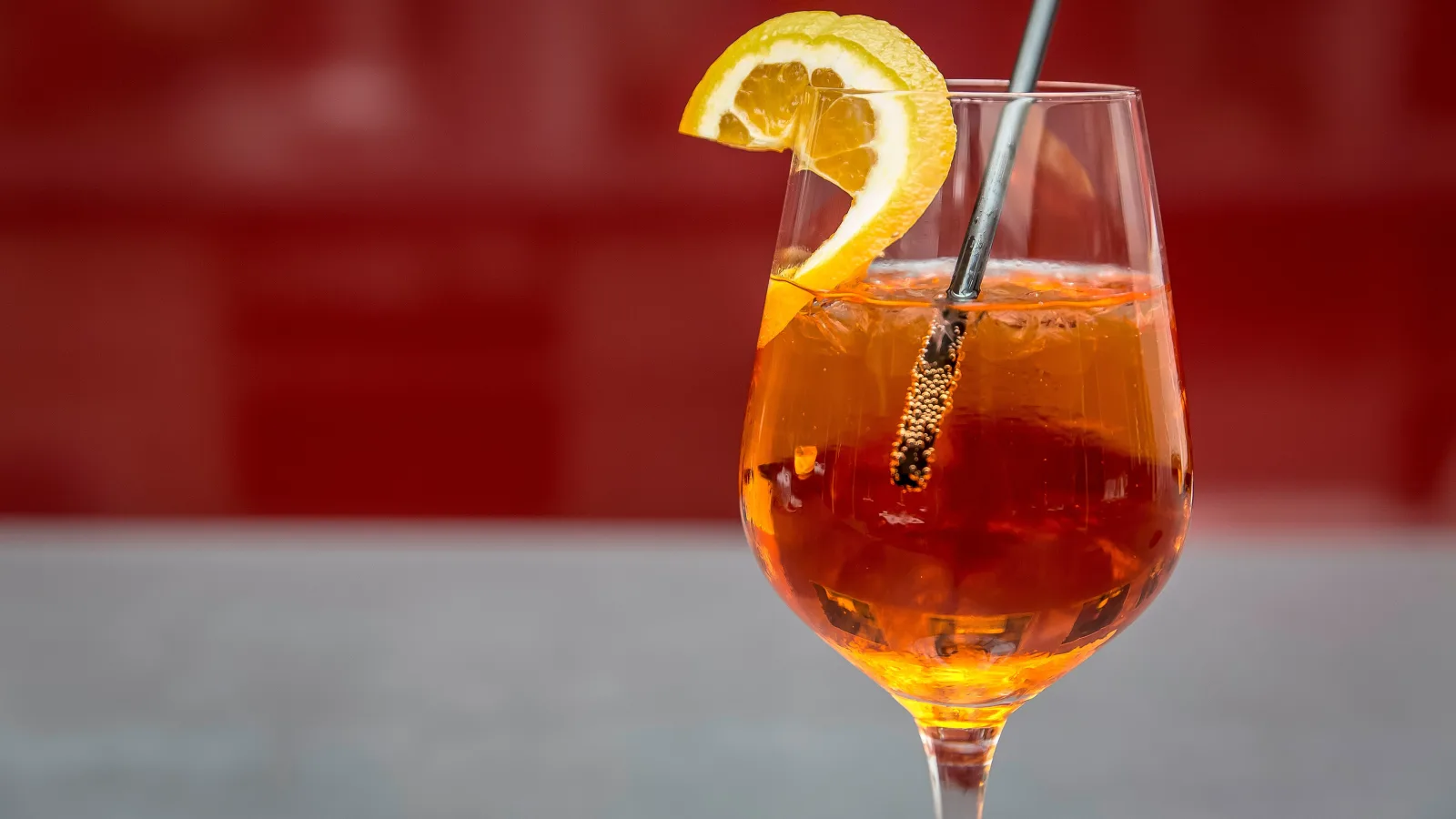 Een hoog glas met een amberkleurige alcoholvrije drank, ijs en een schijf citroen