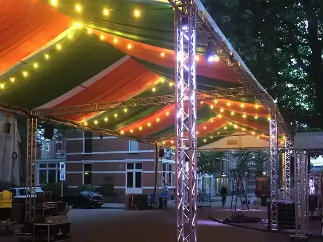 Trusstent met een oranje-groen themazeil en lichtsnoeren