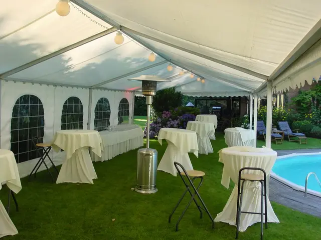 Partytent met statafels en een terrasverwarmer in een tuin naast een zwembad