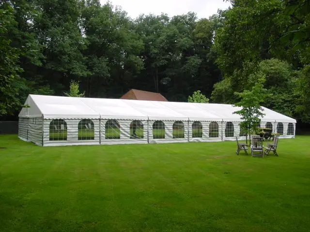 Lange partytent van 10 meter breed op een groot grasveld