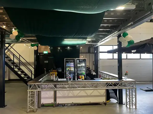 Truss bar met tapkranen, koelkasten en houten bladen in een hal